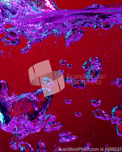 Image of Close up view of the cold and fresh cola with bright bubbles in neon light