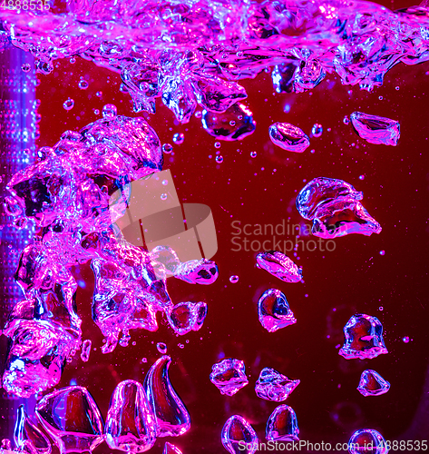 Image of Close up view of the cold and fresh cola with bright bubbles in neon light