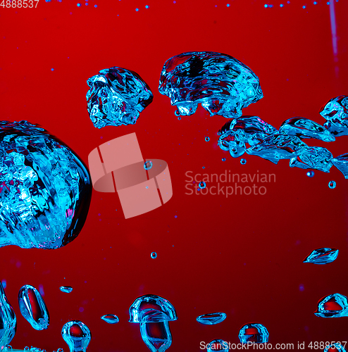 Image of Close up view of the cold and fresh cola with bright bubbles in neon light