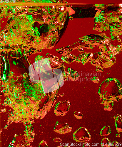 Image of Close up view of the cold and fresh cola with bright bubbles in neon light