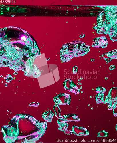 Image of Close up view of the cold and fresh cola with bright bubbles in neon light