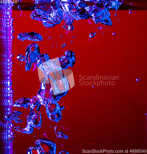 Image of Close up view of the cold and fresh cola with bright bubbles in neon light