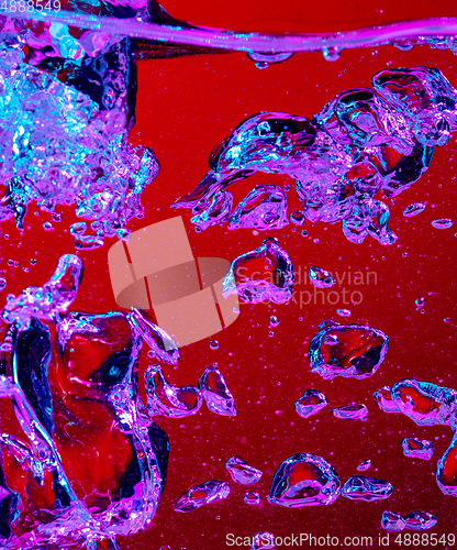 Image of Close up view of the cold and fresh cola with bright bubbles in neon light