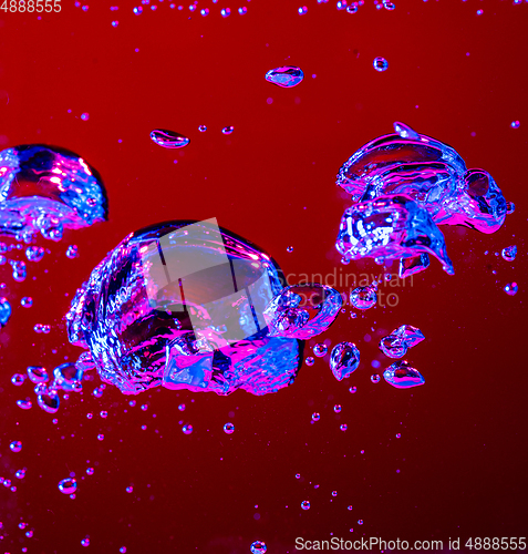 Image of Close up view of the cold and fresh cola with bright bubbles in neon light