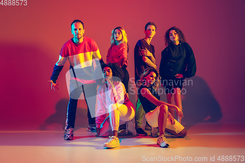 Image of Stylish men and women dancing hip-hop in bright clothes on gradient background at dance hall in neon light