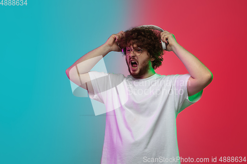 Image of Caucasian young man\'s portrait on gradient studio background in neon
