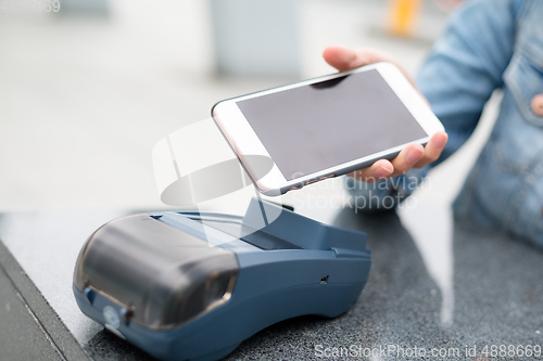 Image of Woman paying with NFC technology on mobile phone