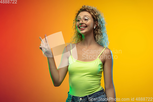 Image of Caucasian young woman\'s portrait on gradient studio background in neon
