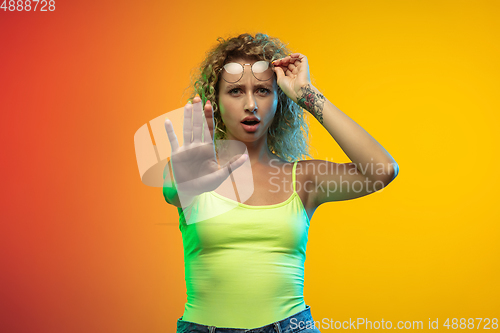 Image of Caucasian young woman\'s portrait on gradient studio background in neon