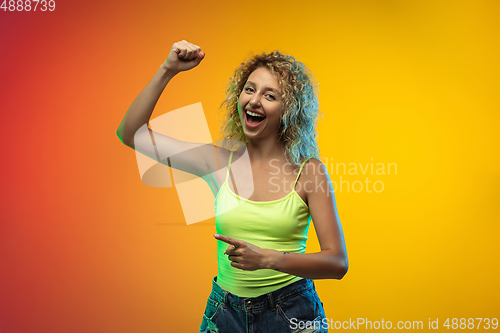 Image of Caucasian young woman\'s portrait on gradient studio background in neon