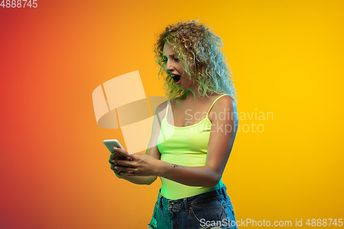 Image of Caucasian young woman\'s portrait on gradient studio background in neon