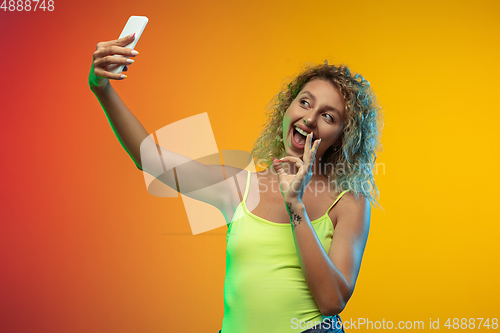 Image of Caucasian young woman\'s portrait on gradient studio background in neon