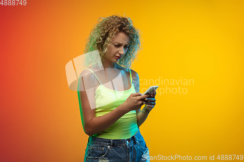 Image of Caucasian young woman\'s portrait on gradient studio background in neon