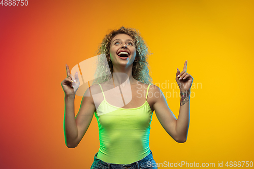 Image of Caucasian young woman\'s portrait on gradient studio background in neon