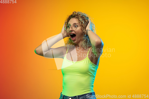 Image of Caucasian young woman\'s portrait on gradient studio background in neon