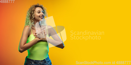 Image of Caucasian young woman\'s portrait on gradient studio background in neon