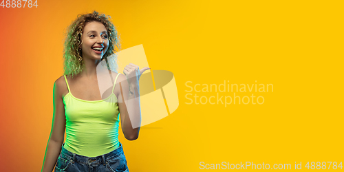 Image of Caucasian young woman\'s portrait on gradient studio background in neon