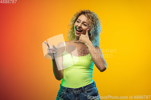 Image of Caucasian young woman\'s portrait on gradient studio background in neon