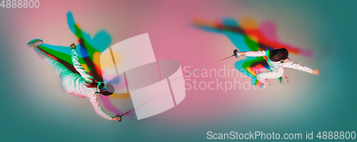 Image of Teen girl in fencing costume with sword in hand on gradient background with neon light, top view