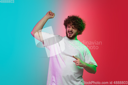 Image of Caucasian young man\'s portrait on gradient studio background in neon