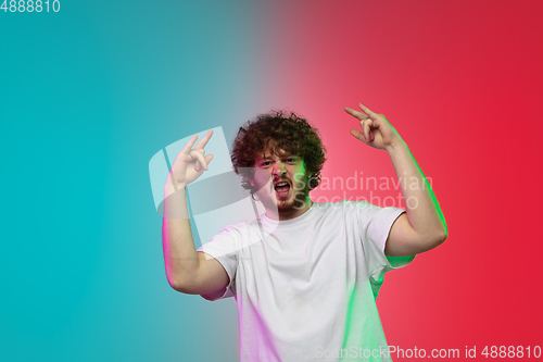 Image of Caucasian young man\'s portrait on gradient studio background in neon