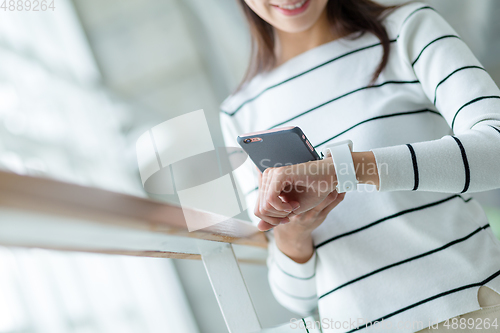 Image of Woman using wearable watch connecting to cellphone