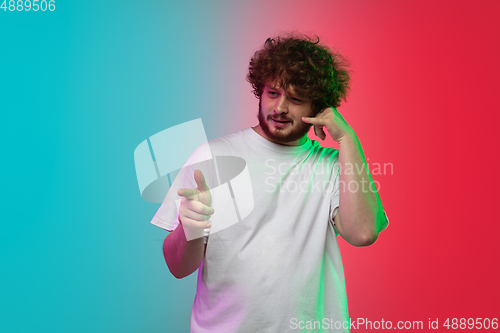 Image of Caucasian young man\'s portrait on gradient studio background in neon