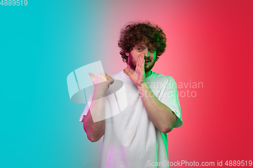 Image of Caucasian young man\'s portrait on gradient studio background in neon