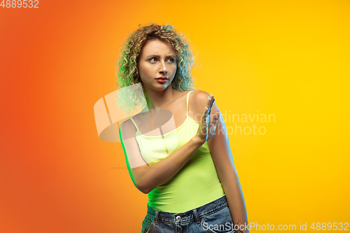 Image of Caucasian young woman\'s portrait on gradient studio background in neon