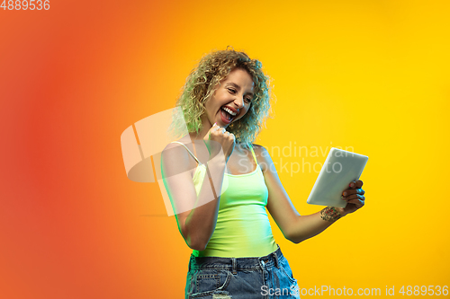 Image of Caucasian young woman\'s portrait on gradient studio background in neon