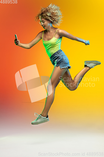 Image of Caucasian young woman\'s portrait on gradient studio background in neon