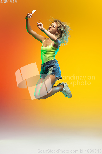 Image of Caucasian young woman\'s portrait on gradient studio background in neon
