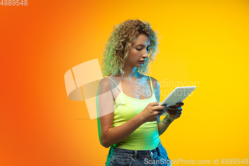 Image of Caucasian young woman\'s portrait on gradient studio background in neon