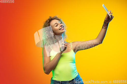 Image of Caucasian young woman\'s portrait on gradient studio background in neon