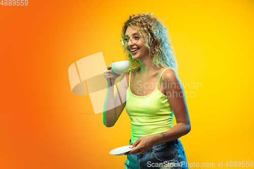 Image of Caucasian young woman\'s portrait on gradient studio background in neon