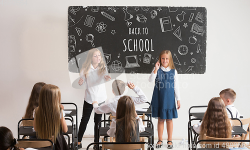 Image of School children in classroom at lesson with worlds Back to school on classboard