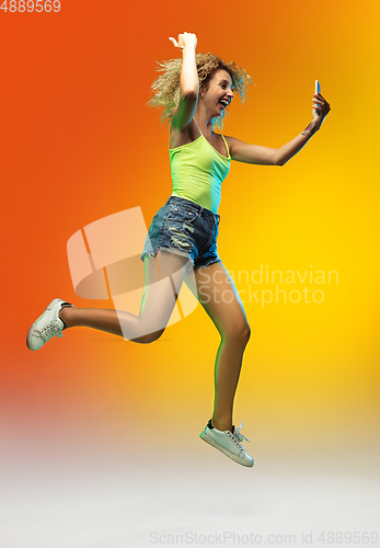 Image of Caucasian young woman\'s portrait on gradient studio background in neon