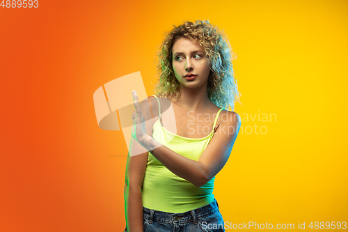 Image of Caucasian young woman\'s portrait on gradient studio background in neon