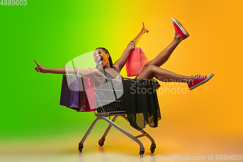 Image of Portrait of young woman in neon light on gradient backgound. The human emotions, black friday, cyber monday, purchases, sales, finance concept.