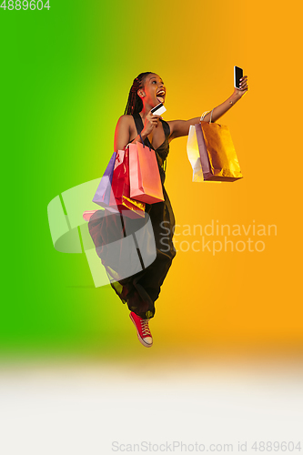 Image of Portrait of young woman in neon light on gradient backgound. The human emotions, black friday, cyber monday, purchases, sales, finance concept.