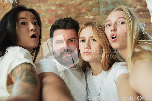 Image of Group of adorable multiethnic friends having fun at home interior background