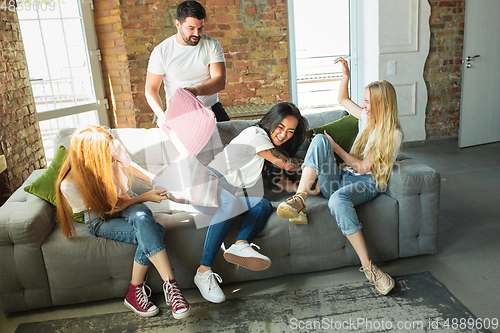 Image of Group of adorable multiethnic friends having fun at home interior background