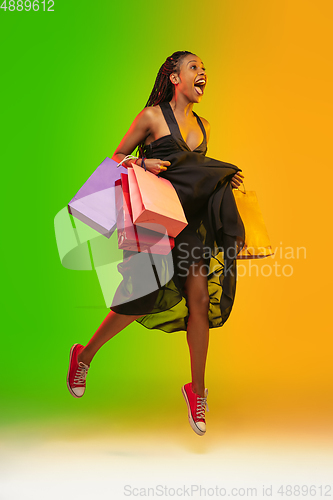 Image of Portrait of young woman in neon light on gradient backgound. The human emotions, black friday, cyber monday, purchases, sales, finance concept.