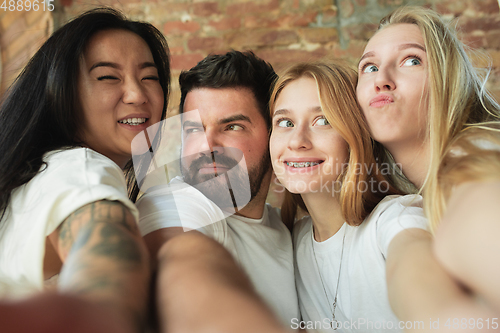 Image of Group of adorable multiethnic friends having fun at home interior background