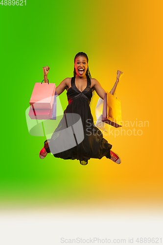 Image of Portrait of young woman in neon light on gradient backgound. The human emotions, black friday, cyber monday, purchases, sales, finance concept.