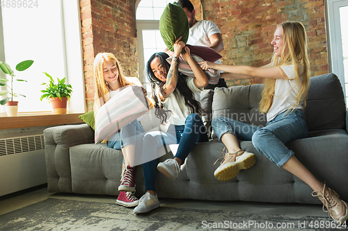 Image of Group of adorable multiethnic friends having fun at home interior background