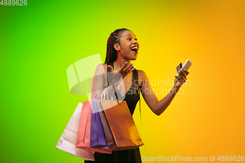 Image of Portrait of young woman in neon light on gradient backgound. The human emotions, black friday, cyber monday, purchases, sales, finance concept.