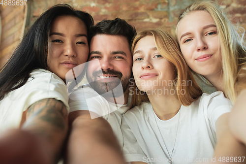 Image of Group of adorable multiethnic friends having fun at home interior background