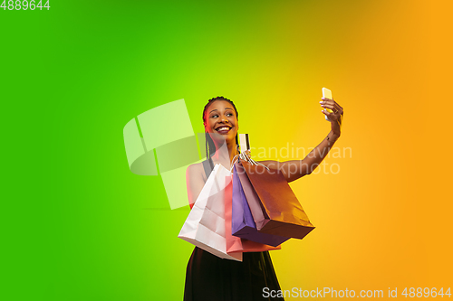 Image of Portrait of young woman in neon light on gradient backgound. The human emotions, black friday, cyber monday, purchases, sales, finance concept.