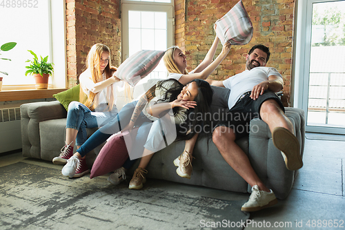 Image of Group of adorable multiethnic friends having fun at home interior background